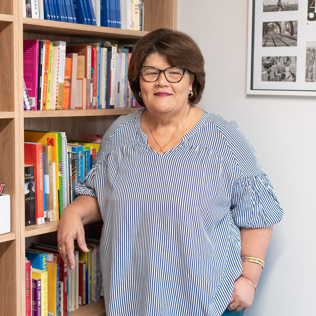 Kathleen Browne standing beside a bookshelf